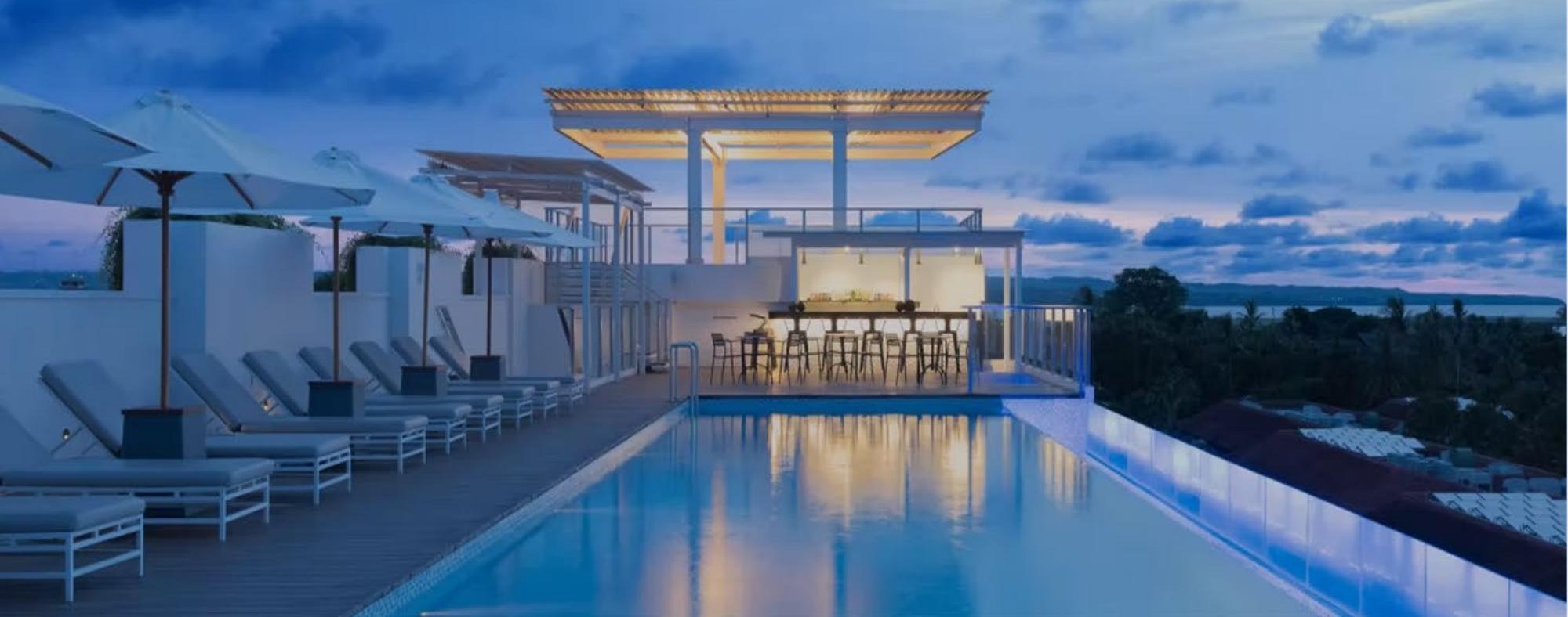 Rooftop infinity pool with bar pavilion at dusk